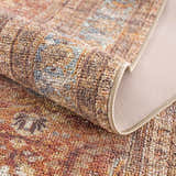 Close-up of the Anshu Peach Washable Area Rug showing its traditional vintage design, beige, blue, and burgundy colors, and soft texture. Fold