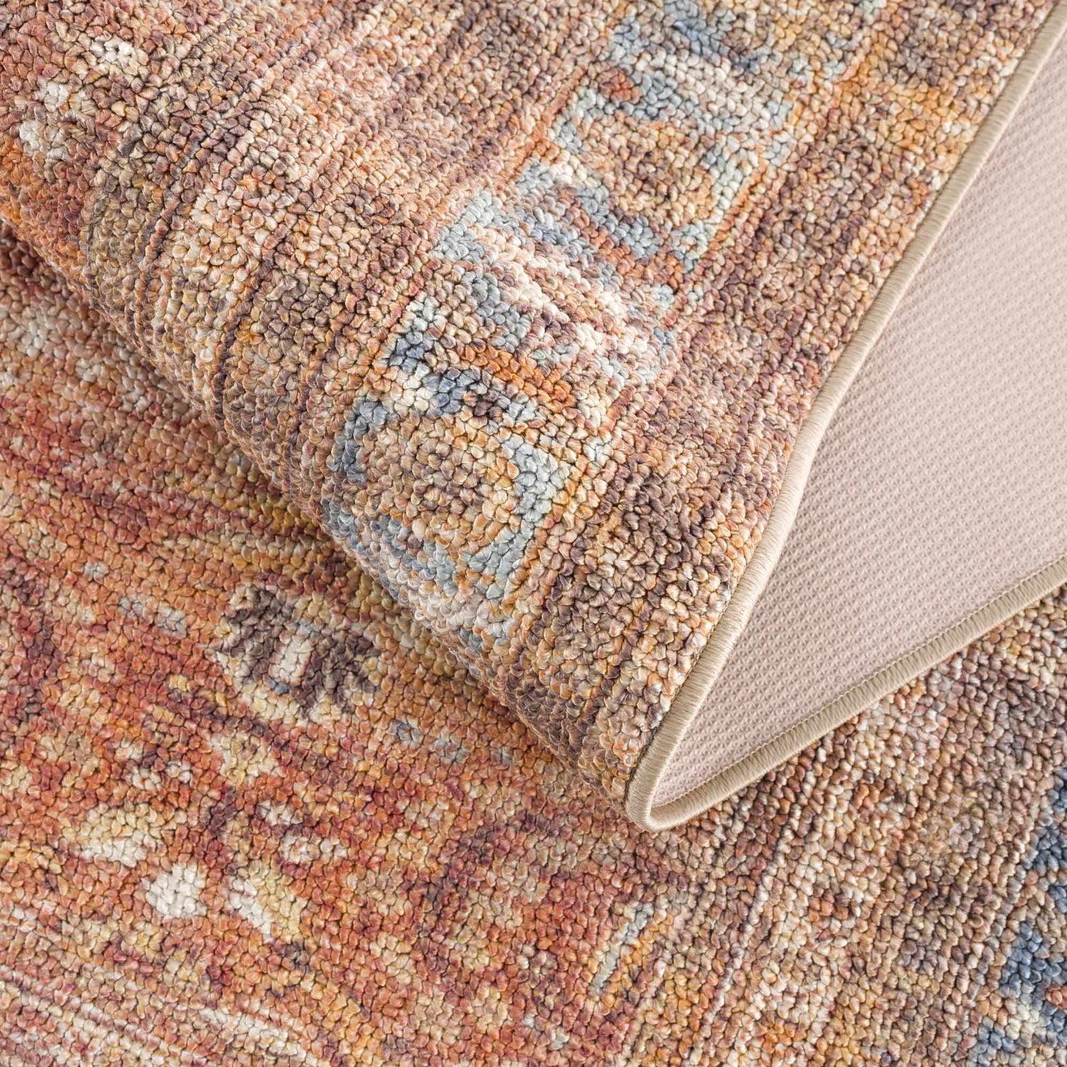 Close-up of the Anshu Peach Washable Area Rug showing its traditional vintage design, beige, blue, and burgundy colors. Fold
