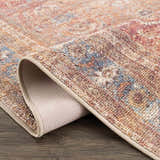 Close-up of the Anshu Peach Washable Area Rug showing its traditional vintage design, beige, blue, and burgundy colors, and soft texture. Fold