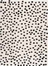 Close-up of the Cansu Black & White Dotted Area Rug. The shag rug has black dots on an off-white background. Design-Rectangle-46