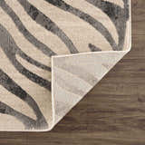 Close-up of the Gray Ecorse Zebra Print Area Rug showing the gray and beige zebra pattern and rug backing. Fold