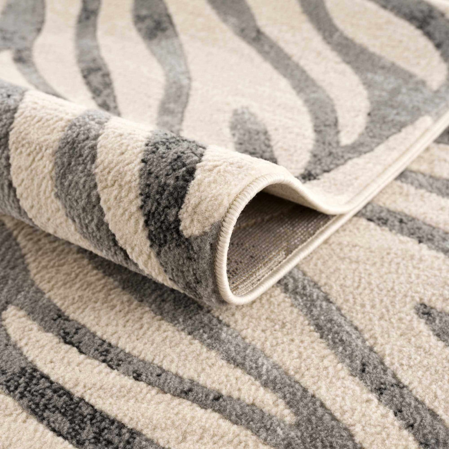 Close-up of the Gray Ecorse Zebra Print Area Rug showing the texture and gray and beige zebra pattern. Fold