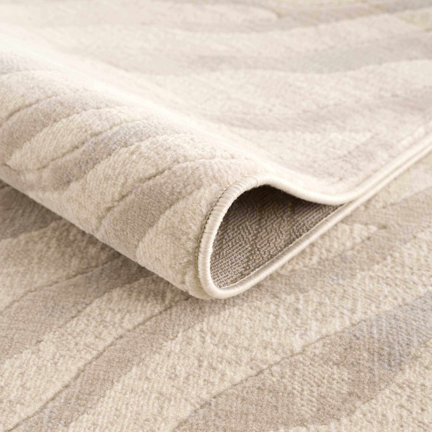 Close-up of the Beige Manteca Zebra Print Area Rug showing its soft texture, beige and light gray pattern, and bound edge. Fold