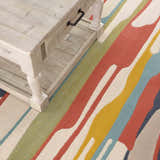 Close-up of Southfields Colorful Modern Area Carpet with aqua, mustard, and peach stripes under a light beige wooden coffee table. Styleshot