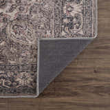 Close-up of the Greenpoint Dusty Blue Washable Rug showing its beige, black, and red oriental pattern and machine-woven texture. Fold