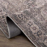 Close-up of the Greenpoint Dusty Blue Washable Rug. Beige, black, and red oriental pattern with a chenille-polyester texture. Fold