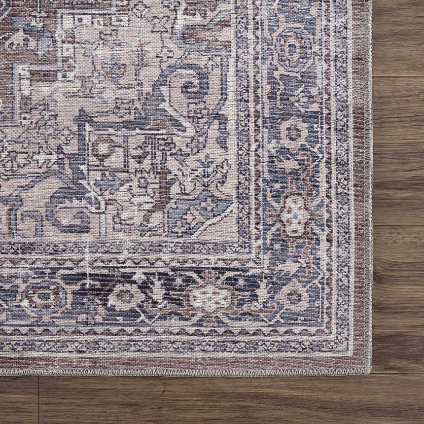 Close-up of the Abner Washable Area Rug showing its farmhouse-style traditional pattern in brown, denim, and ivory tones. Swatch