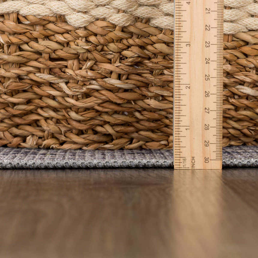 Close-up of the Abner Washable Area Rug showing the charcoal color, woven texture, and rug thickness with a ruler. Pile