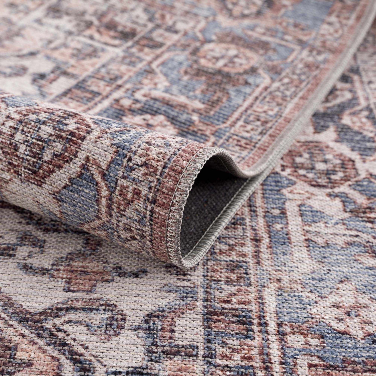 Close-up of the Viho Vintage Flat Pile Washable Rug, showing a traditional pattern in brown, blue, and peach tones. Chenille polyester texture. Fold