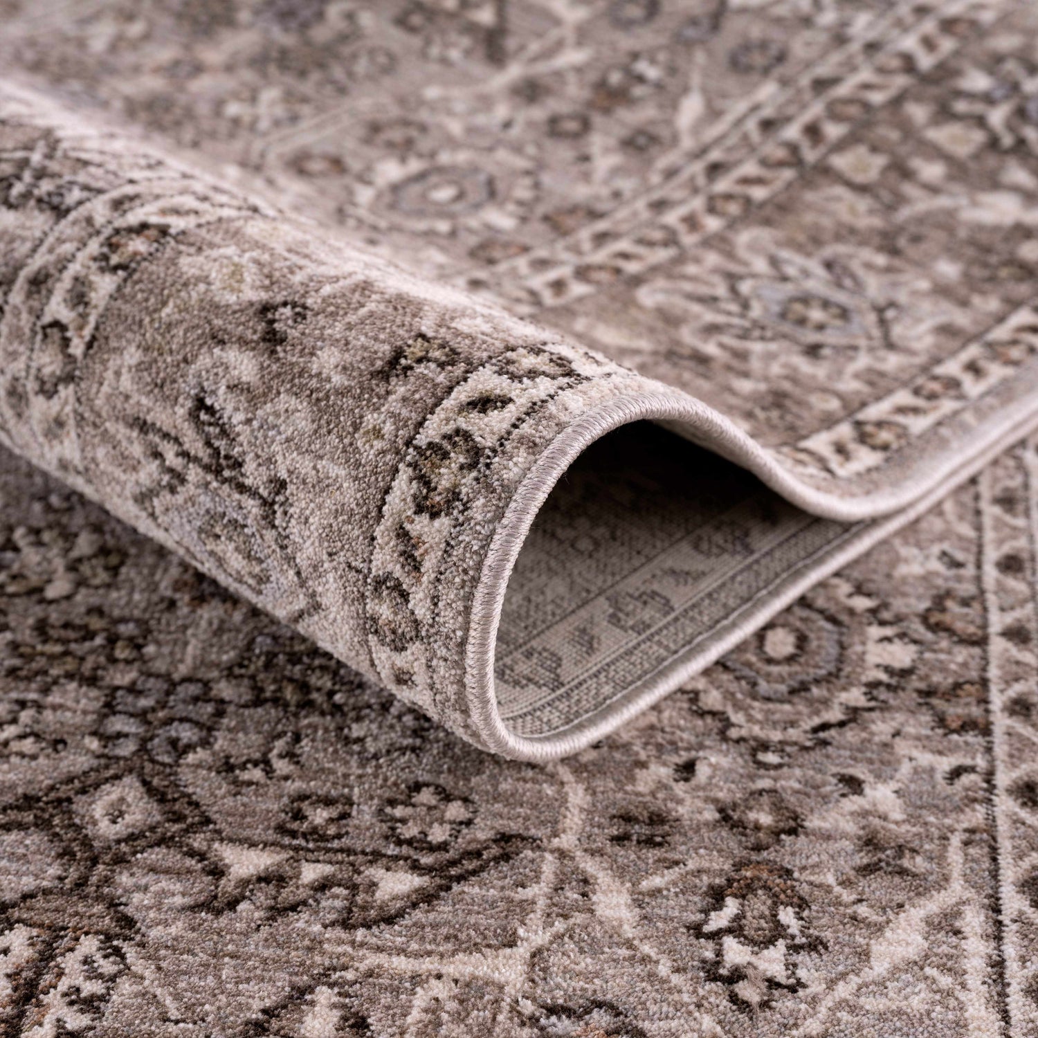 Close-up of the Lugo Luxe Area Rug, showcasing its traditional charcoal and light gray oriental pattern and soft texture. Fold