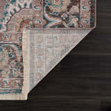 Close-up of the Baychester Brown Area Rug showing its traditional, oriental pattern, fringe, and dark brown, denim, and sage colors. Fold