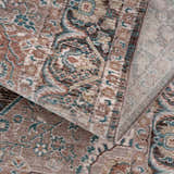 Close-up of the Baychester Brown Area Rug showing its traditional oriental pattern, dark brown, denim, and dusty pink colors. Fold