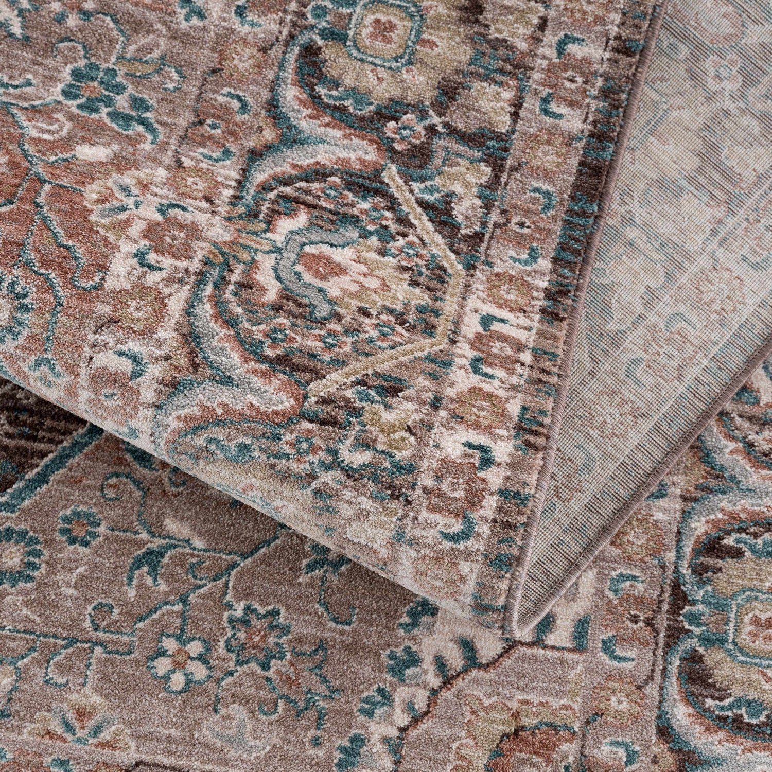 Close-up of the Baychester Brown Area Rug showing its traditional oriental pattern, dark brown, denim, and dusty pink colors. Fold