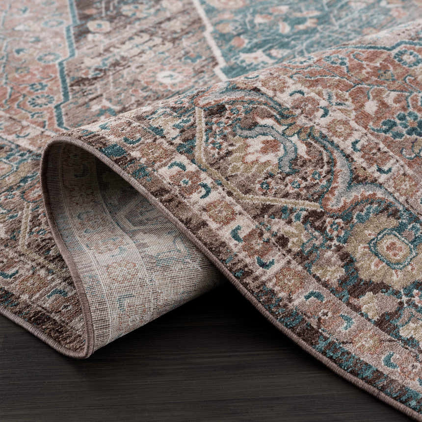 Close-up of the Baychester Brown Area Rug showing its traditional oriental pattern, brown, denim, and dusty pink colors. Fold