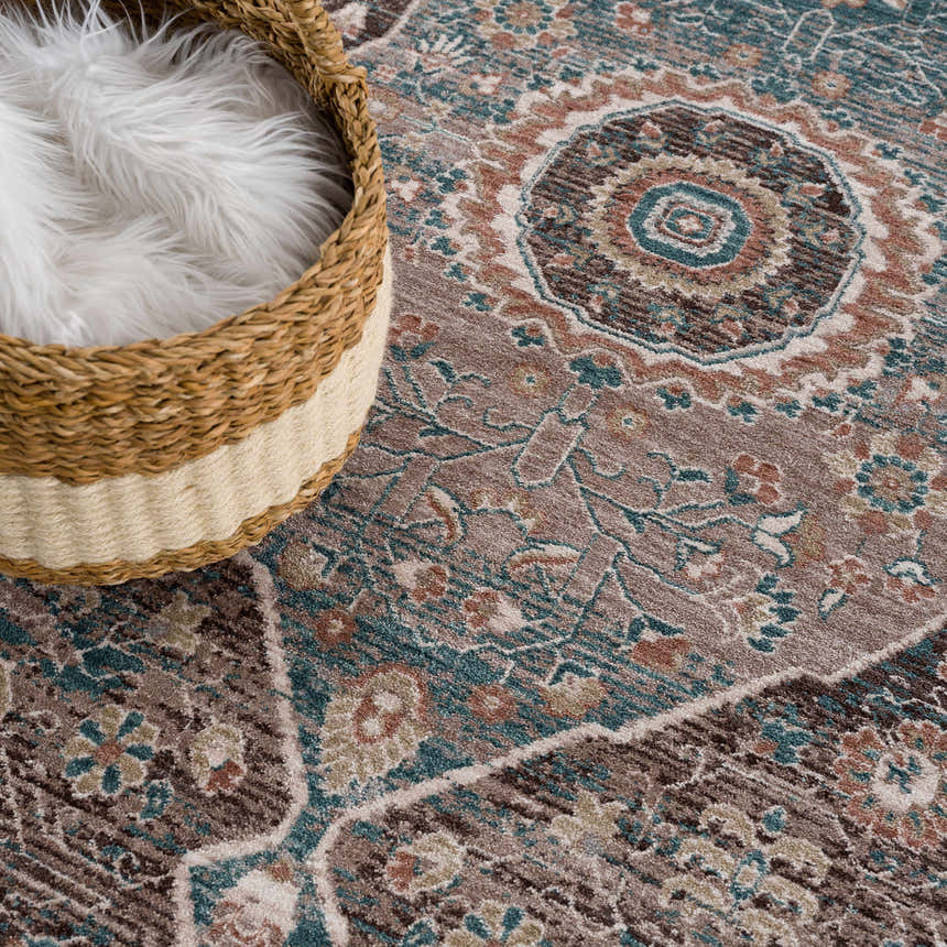 Close-up of the Baychester Brown Area Rug with oriental design, brown, teal, and pink colors, and a basket with white faux fur. Styleshot