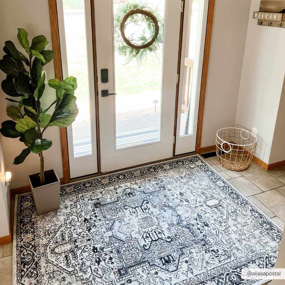 Entryway with a black and light beige Cabacungan Washable Area Rug, a potted plant, and a white door with a wreath. Roomscene-Rectangle