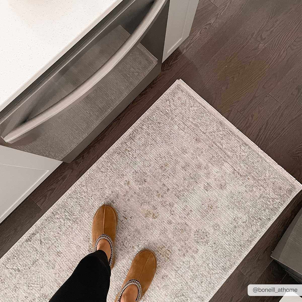 Kitchen scene with Coby Sage Avant Garde rug on dark wood floor. Person wearing brown slippers. Luxe, traditional style. Roomscene-Runner