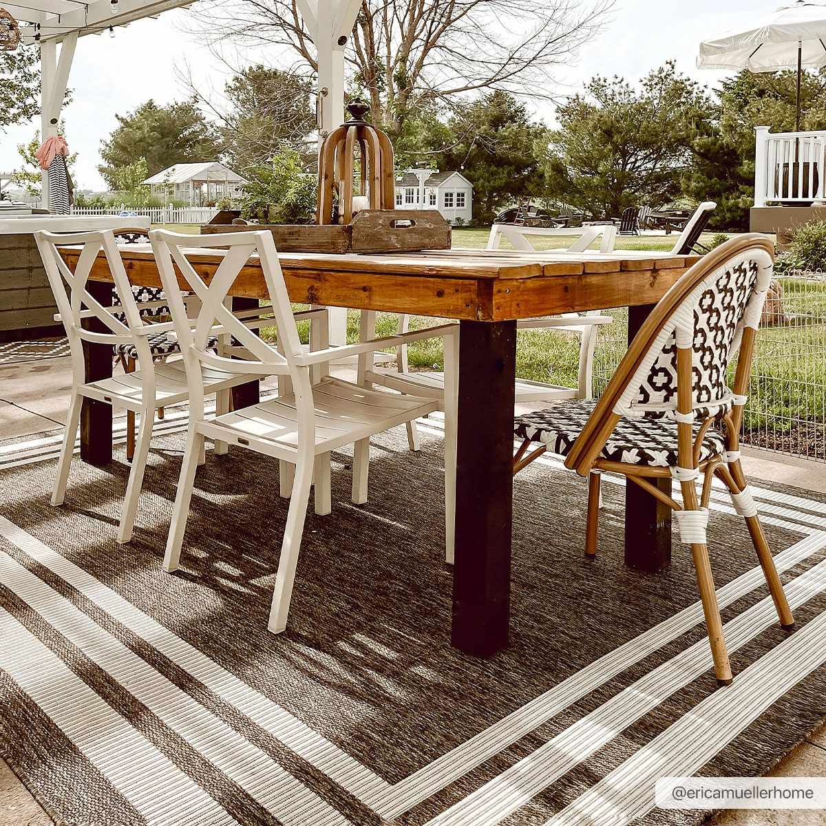 Outdoor dining area with a wood table and white chairs on a Coonamble Bordered Antrasit Rug. Roomscene-Rectangle