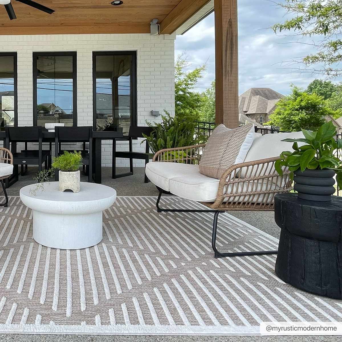 Outdoor patio scene with a geometric Anah Cream outdoor rug, wicker furniture, and white coffee table. Roomscene-Rectangle