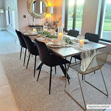 Dining room with a Cream Braided Faux Jute Rug under a table set for a dinner party. Neutral tones and soft lighting. Roomscene-Rectangle
