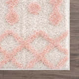 Close-up of the Darva Pink Plush Area Carpet showing the shag texture and geometric pink and white pattern. Swatch