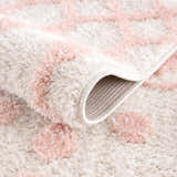 Close-up of the plush Darva Pink Area Carpet showing texture, pink geometric pattern, and backing. Fold