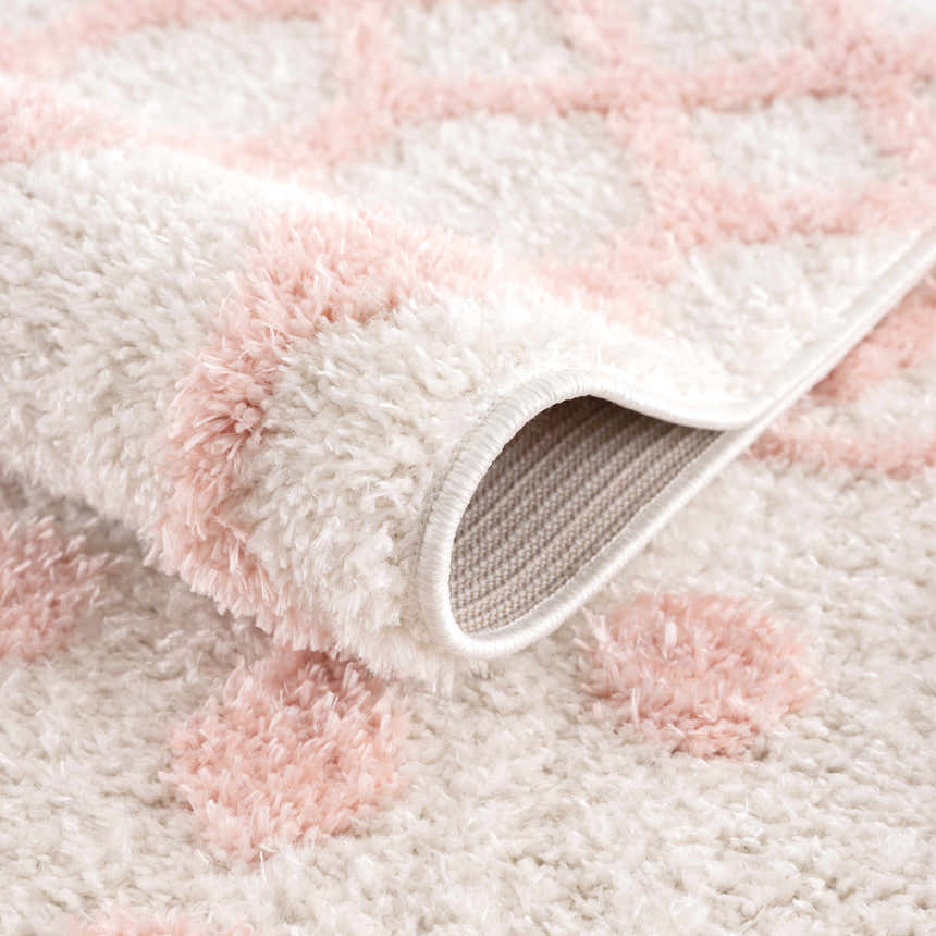 Close-up of the plush Darva Pink Area Carpet showing texture, pink geometric pattern, and backing. Fold