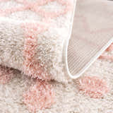 Close-up of the plush Darva Pink Area Carpet showing its soft texture, pink and white pattern, and woven backing. Fold