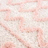 Close-up of the Darva Pink Plush Area Carpet showing its shag texture and bohemian pink and white zigzag pattern. Texture