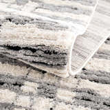 Close up of the textured Nava Area Rug, a geometric design in beige, black, and bone. Fold