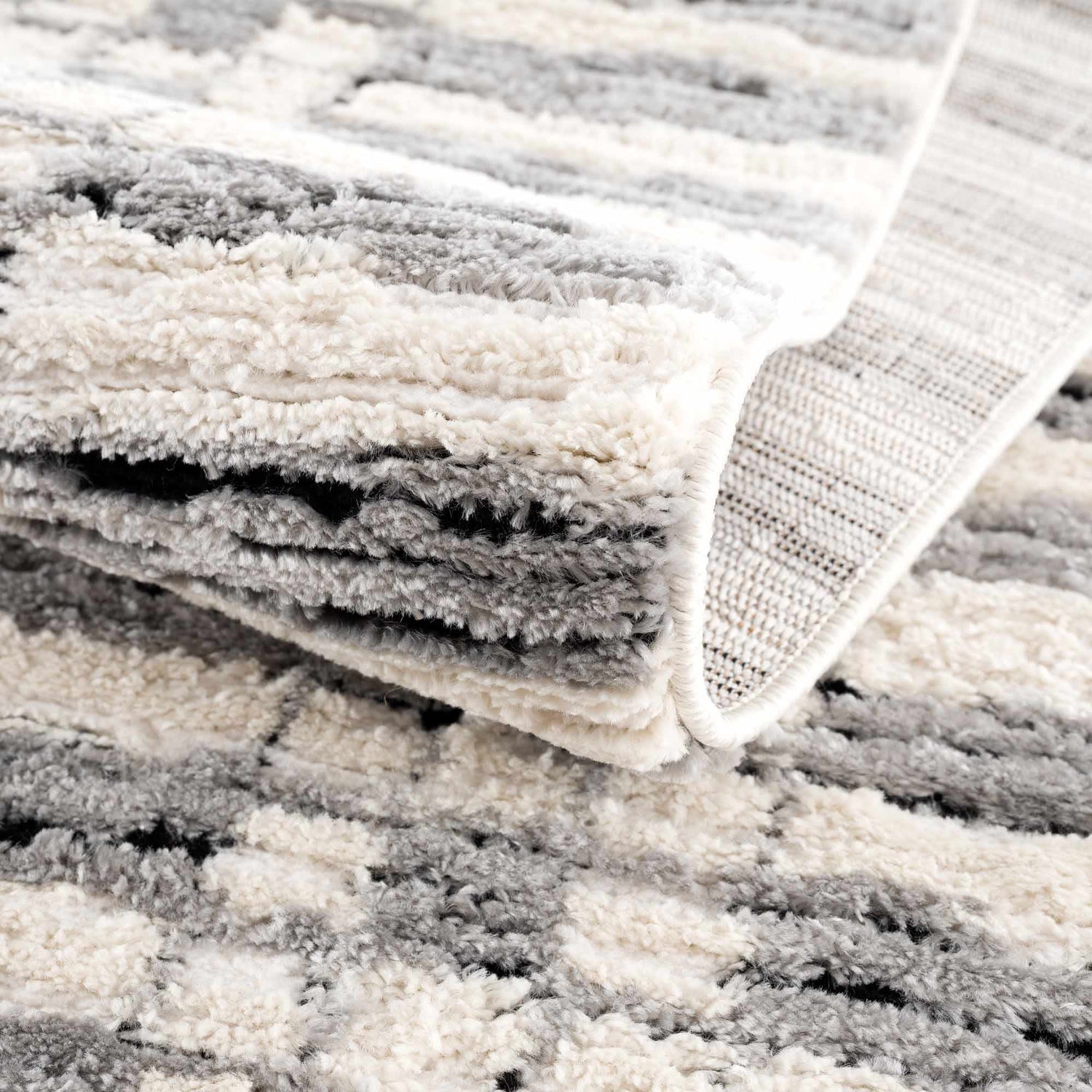 Close up of the textured Nava Area Rug, a geometric design in beige, black, and bone. Fold