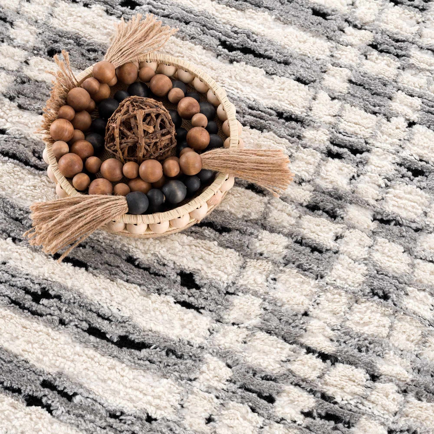 Close-up of the Nava Area Rug showing its beige, black, and bone geometric pattern and textured, machine-woven construction. Styleshot