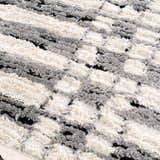 Close-up of the Nava Area Rug. Beige, bone, and black geometric pattern. Soft, textured, machine-woven pile. Texture