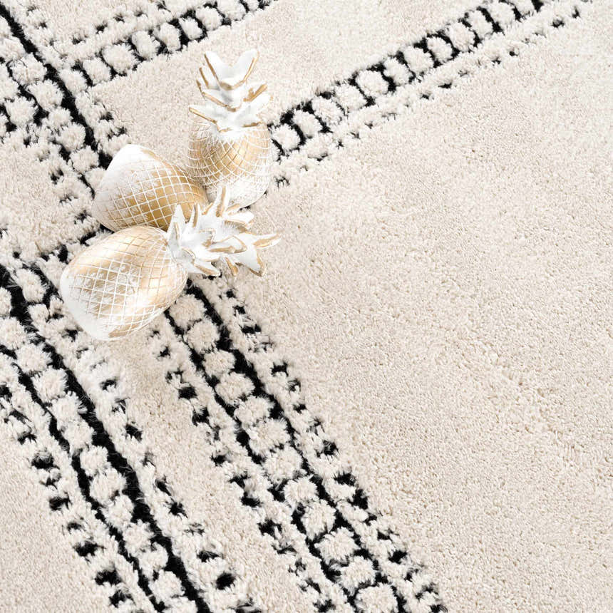 Close-up of Ryuu Black & White Area Rug. Beige rug with black geometric pattern and textured pile. White and gold pineapples. Styleshot