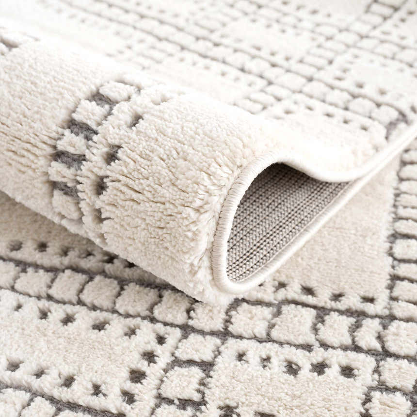 Close-up of the Ryuu Ivory & Gray Area Rug showing its plush texture and geometric pattern in beige and gray tones. Fold