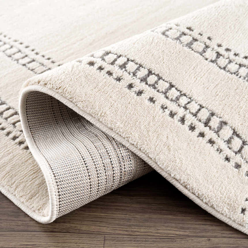 Close-up of the Ryuu Ivory & Gray Area Rug showing its bone color, geometric gray pattern, and soft texture. Fold