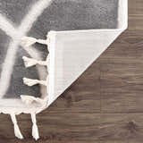 Close-up of the Azana Modern Gray Area Rug showing the geometric design, tassels, and durable polypropylene backing. Fold