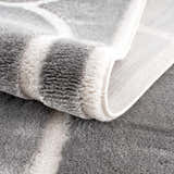 Close-up of the plush texture and geometric pattern of the gray and cream Azana Modern Area Rug. Fold