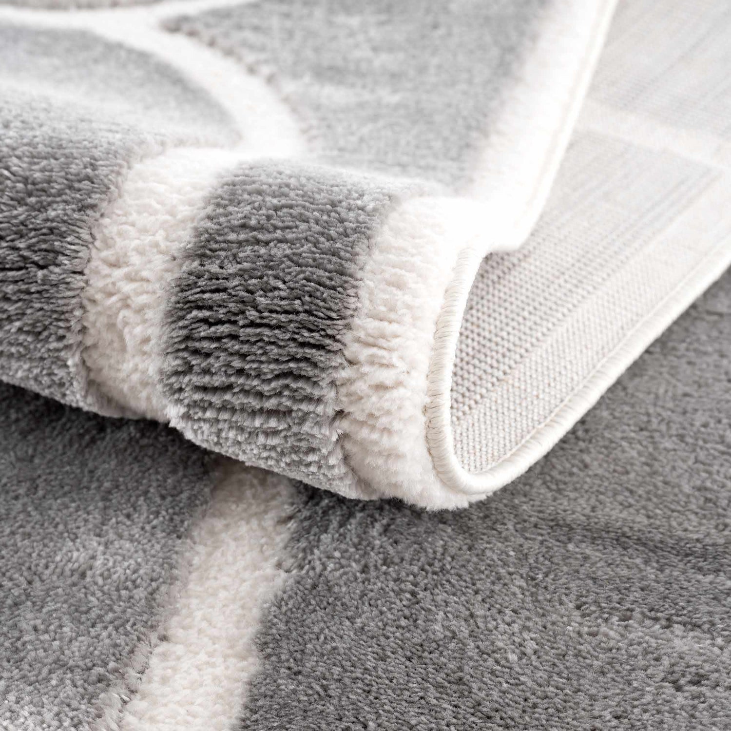 Close-up of the plush texture and geometric pattern of the gray and cream Azana Modern Area Rug. Fold