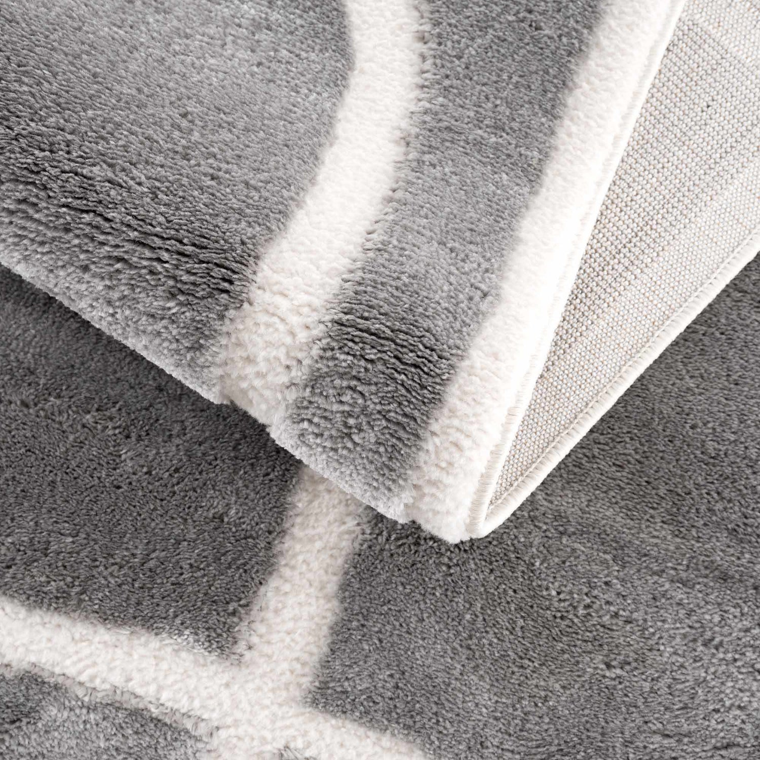 Close-up of the Azana Modern Gray Area Rug showing its geometric pattern, soft texture, and cream and gray colors. Fold