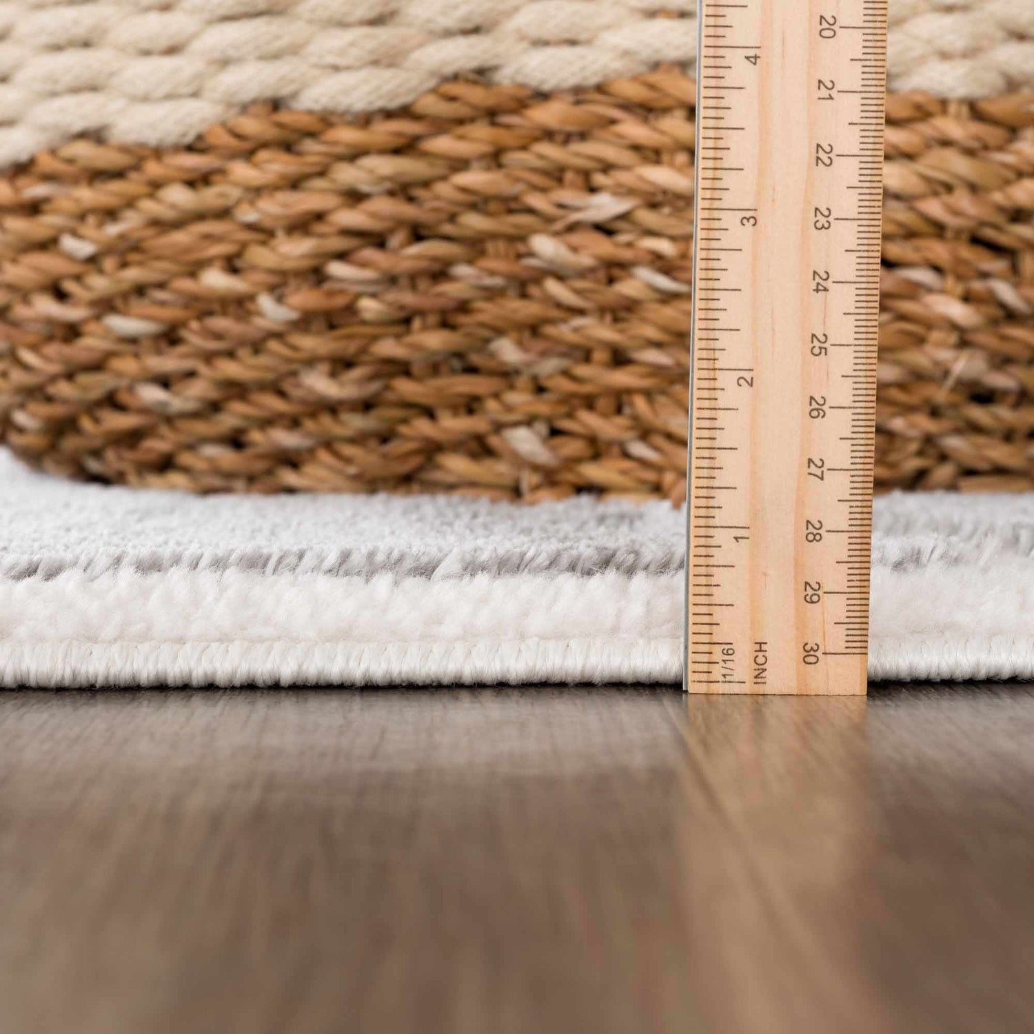 Close-up of the Azana Modern Gray Area Rug showing rug thickness with ruler and basket. Cream and gray rug texture. Pile