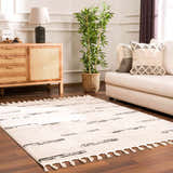 Living room scene with Riad Black Striped White Rug. Beige sofa, wood cabinet, and plant create a cozy, modern space. Roomscene-Rectangle
