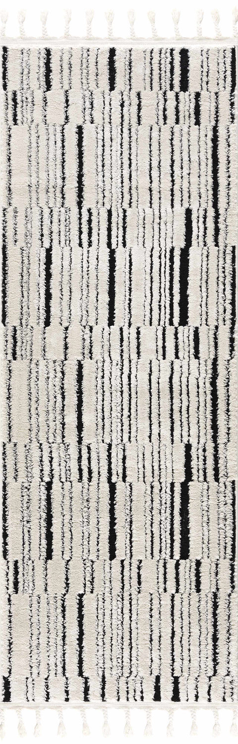 Close-up of the Bansi Area Rug. Beige rug with a black geometric pattern and tassels. Bohemian style. Design-Runner