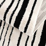 Close-up of the Bansi Area Rug: beige and black stripes, plush texture, machine woven construction. Fold