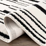 Close-up of the Bansi Area Rug showing its geometric black and bone pattern and textured polypropylene weave. Fold