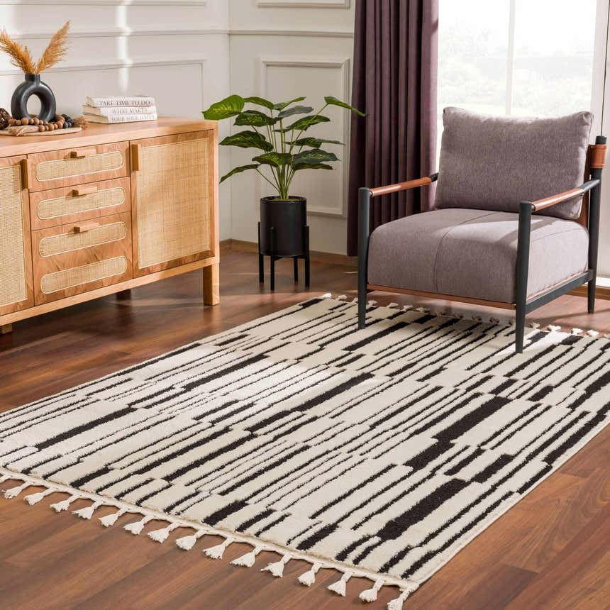 Living room scene with a Bansi Area Rug, beige walls, wood cabinet, gray chair, and wood floors. Roomscene-Rectangle