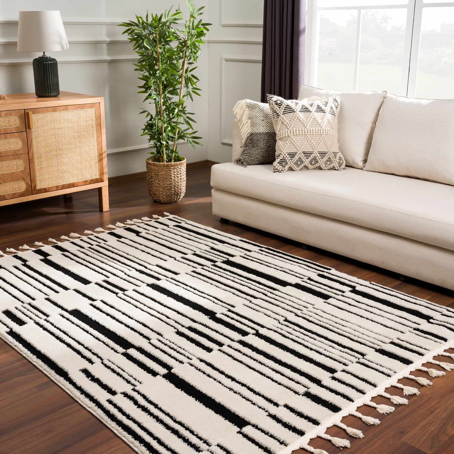 Living room scene with a Bansi Area Rug in beige and black, sofa, wood cabinet, and plant. Roomscene-Rectangle