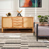 Living room scene with Bansi Area Rug, beige and black geometric pattern, styled with a wood cabinet and gray chair. Roomscene-Rectangle