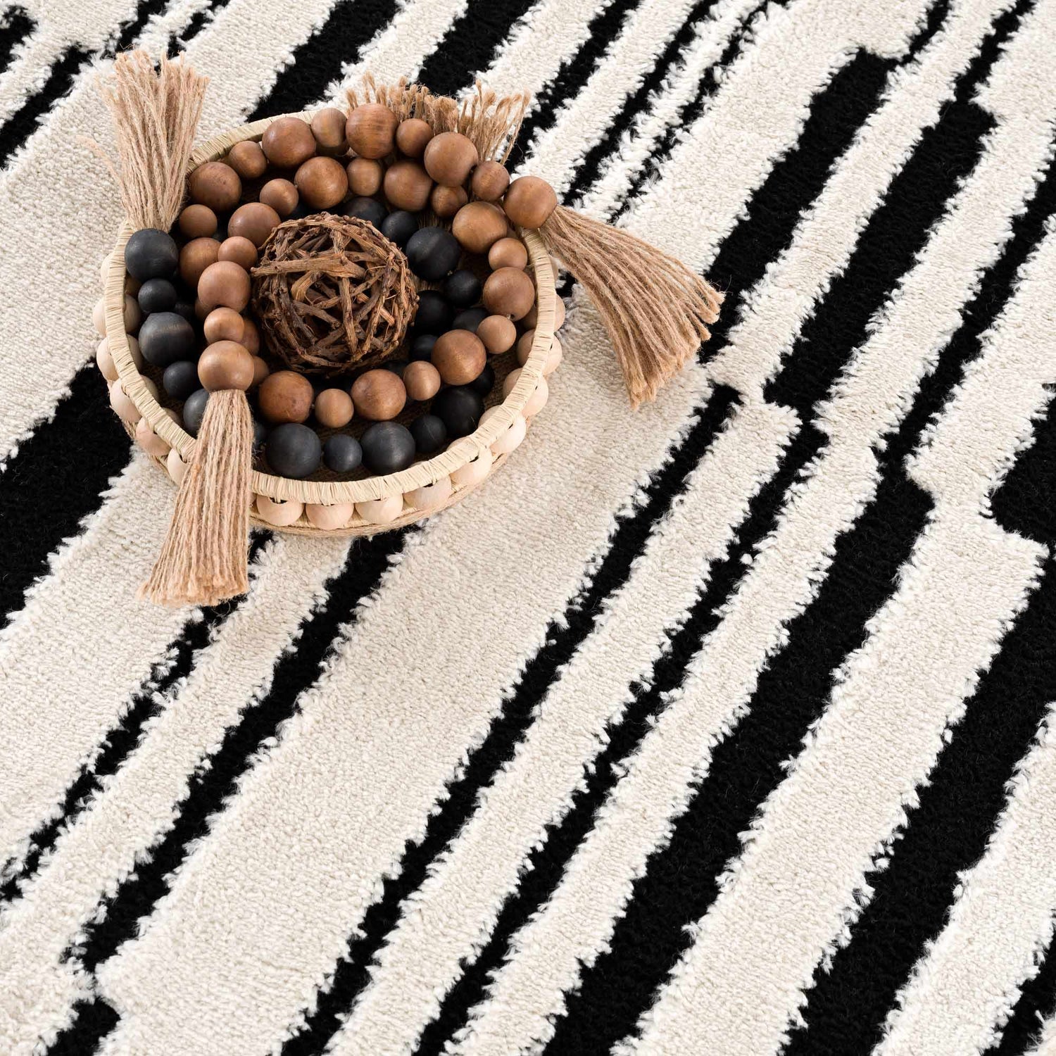 Close up of the Bansi Area Rug. Beige rug with a bold black geometric stripe pattern and textured weave. Styleshot