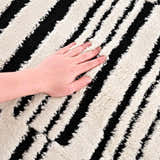 Close-up of the Bansi Area Rug showing its beige and black geometric pattern and soft, textured pile. Texture